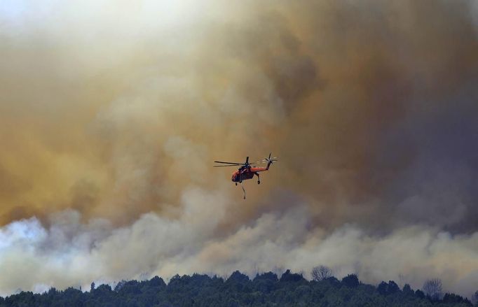 A fire fighting helicopter flies over the Wood Hollow fire, north of Fairview, Utah, June 26, 2012. More than 500 structures have been threatened by the Wood Hollow fire, forcing up to 1,500 people from homes. REUTERS/George Frey (UNITED STATES - Tags: ENVIRONMENT DISASTER) Published: Čer. 26, 2012, 9:34 odp.