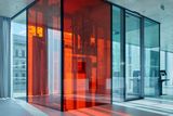 Vedle nich je výtahová šachta z barevného skla, která oživuje interiér a zároveň ho propojuje s podzemními garážemi s kapacitou 120 míst.