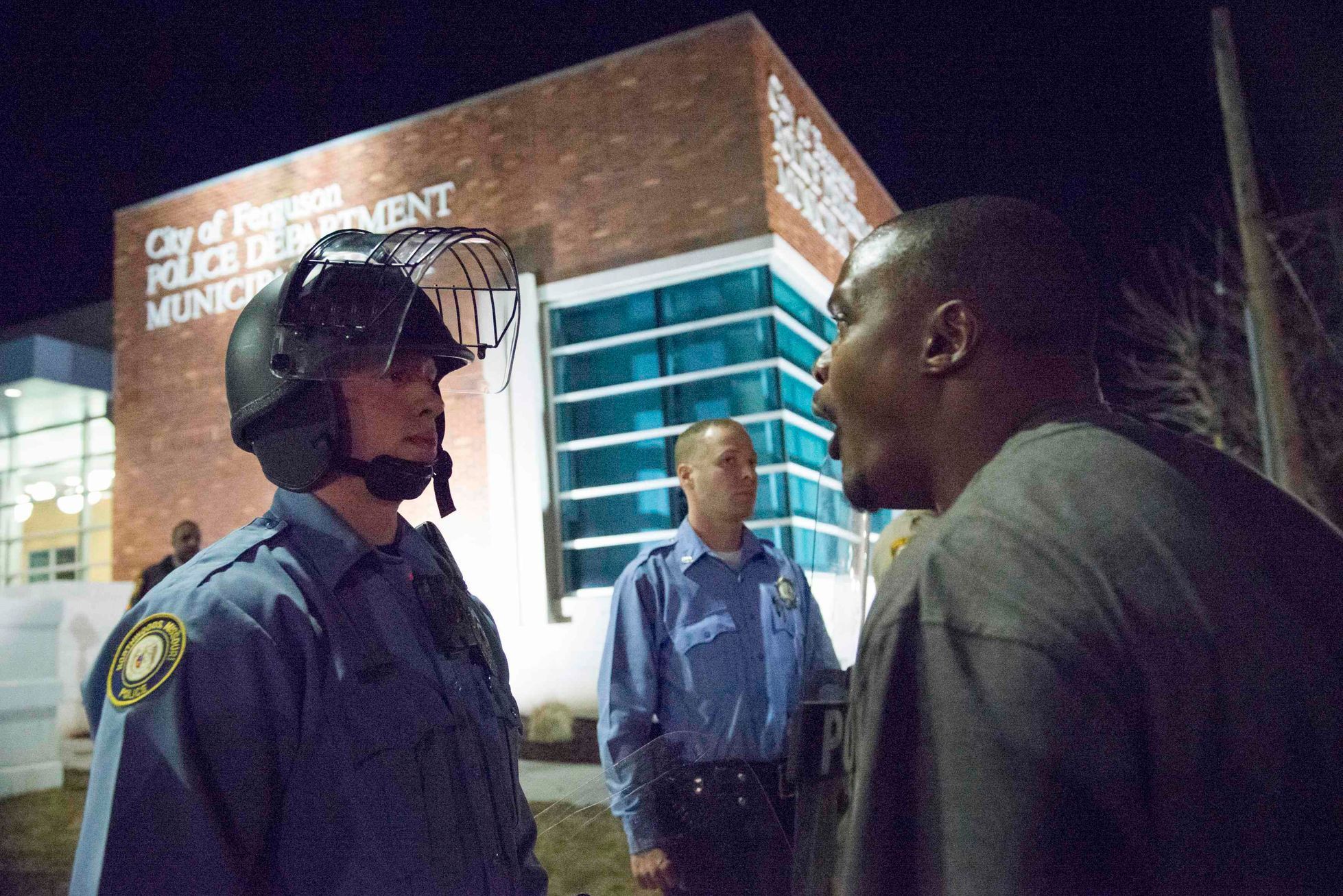 A protester confronts a police officer outside the City of Ferguson Police Department and Municipal Court in Ferguson