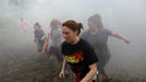 Runners are chased by a zombie (C) at the "Run for Your Lives" 5K obstacle course race in Amesbury, Massachusetts May 5, 2012. Runners face man-made and natural obstacles on the course, while being chased by zombies, who try to take "health" flags off the runners belts. REUTERS/Brian Snyder (UNITED STATES - Tags: SPORT SOCIETY) Published: Kvě. 5, 2012, 11:28 odp.