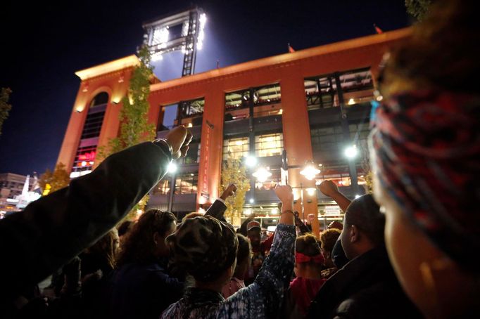 Demonstranti protestují proti zastřelení Michala Browna u stadionu Busch když přijíždějí fanoušci baseballu na začátek baseballové ligy ve Fergusnu 11.října