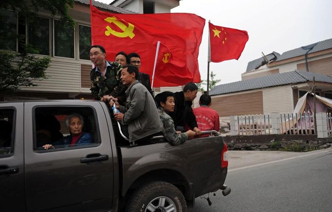 Volunteers hold a Chinese national flag and Chinese communist party flags as they head to Lushan county after Saturday's earthquake, Ya'an, Sichuan province, April 22, 2013. Hundreds of survivors of an earthquake that killed nearly 200 people in southwest China pushed into traffic on a main road on Monday, waving protest signs, demanding help and shouting at police. Picture taken April 22, 2013. REUTERS/Stringer (CHINA - Tags: DISASTER SOCIETY) Published: Dub. 23, 2013, 3:20 dop.