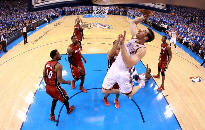 Nick Collison smečuje do koše za přihlížení hráčů Miami.