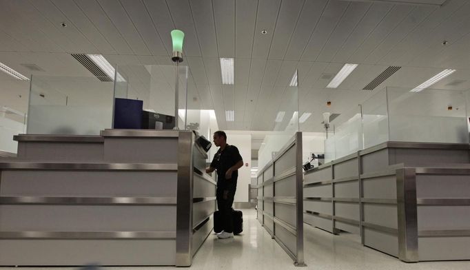 Luis Salgado, nicknamed Chucho, stands at the counter of U.S. Immigration upon arriving at Miami airport on a direct flight from Havana, March 13, 2013. Chucho was granted a U.S. visa based on his father's status as legal resident in Texas, and he was reunited in Miami with his father, Jesus Salgado, who had escaped Cuba on a frail boat ten years earlier. The Salgados are among many Cubans taking advantage of Cuba's new travel policy in place since last January, which allows citizens to leave the country with just a passport and no need for much-hated exit visas required since 1961. Picture taken March 13, 2013. REUTERS/Desmond Boylan (UNITED STATES - Tags: POLITICS SOCIETY) Published: Dub. 11, 2013, 1:48 odp.