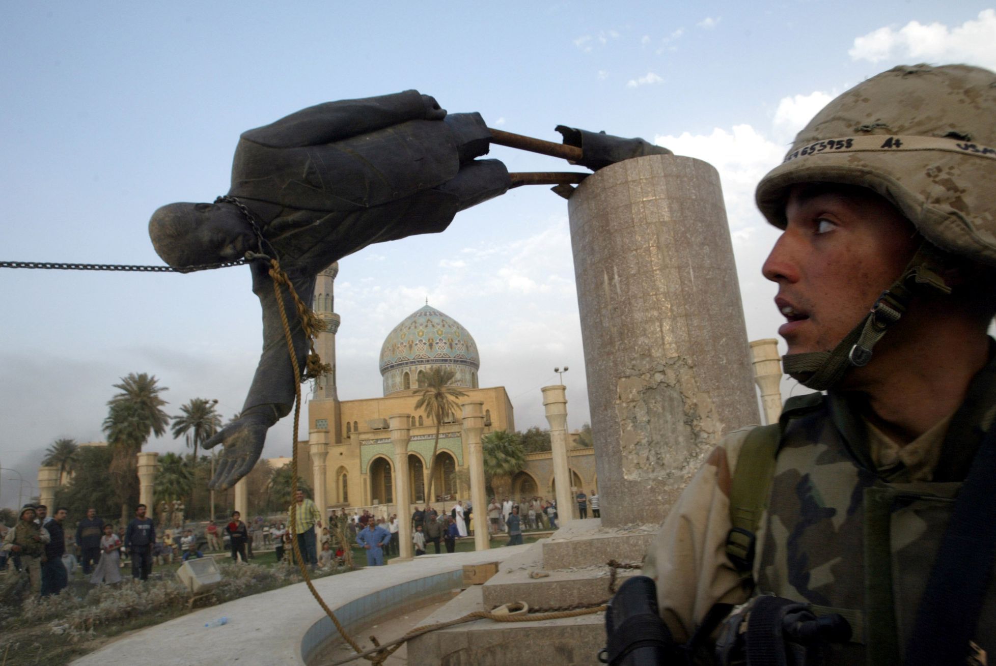 Americký voják sleduje stržení sochy Saddáma Husajna v Bagdádu (archivní foto).