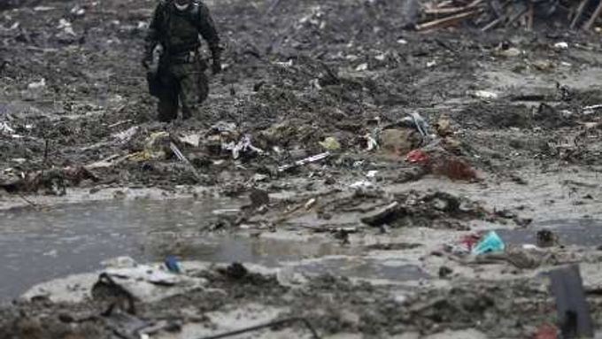 Japonský voják pátrající v nánosech bahna a odpadků po tělech mrtvých