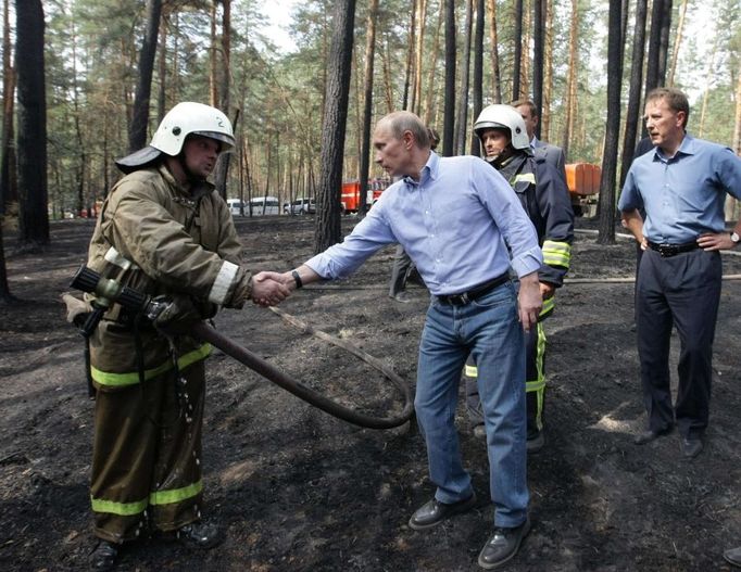 Na jedno ze spálenišť se vypravil premiér Vladimir Putin. Na snímku se zdraví z hasiči zasahujícími u Voroněže.