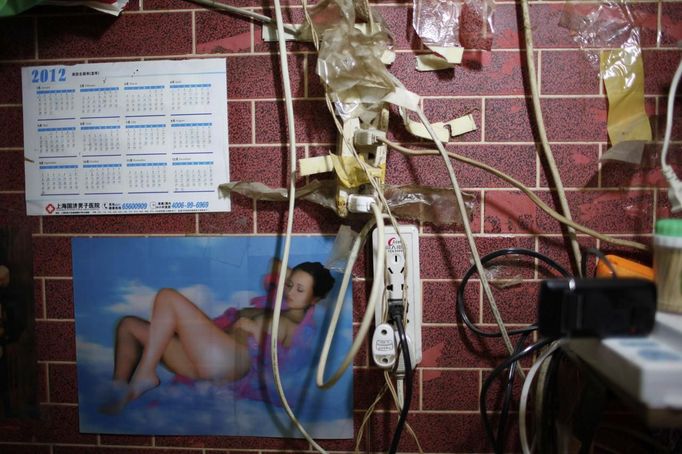 A picture of a naked woman is seen next to electrical wires in the home of Xiao Cao, a 57-year-old gay man, in Shanghai April 22, 2012. China's gay community has long been on the edges of society but it is gradually becoming more accepted. Cao, who is an unemployed drag queen, is one whose life lifts the curtain on a less romanticised view of Chinese homosexuals. Living in an eight square metre apartment behind a public toilet and with a monthly income of 500 yuan ($79) from social insurance, he passes his days dancing in public and spending time with friends at gay clubs. Picture taken April 22, 2012. REUTERS/Aly Song (CHINA - Tags: SOCIETY) TEMPLATE OUT. CHINA OUT. NO COMMERCIAL OR EDITORIAL SALES IN CHINA. ATTENTION EDITORS PICTURE 05 OF 28 OF PACKAGE 'GAY AND OUT IN CHINA' TO FIND ALL IMAGES SEARCH 'GAY OUT CHINA' Published: Čer. 1, 2012, 12:35 dop.