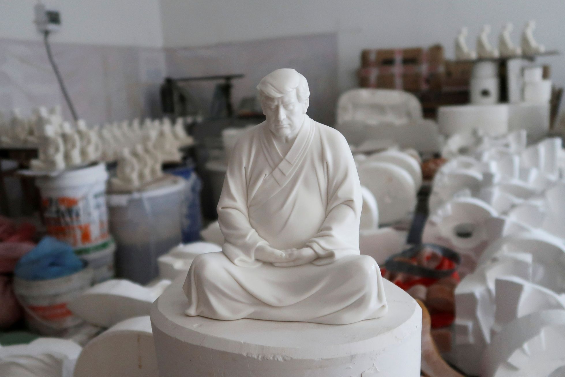 Čínský nábytkář Hong Jinshi vyrábí sošky Donalda Trumpa v buddhistické póze.