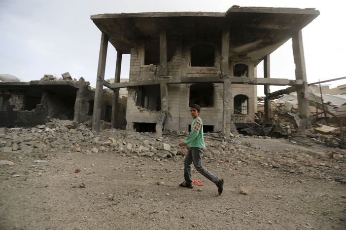 A boy walks past a building damaged by a recent Saudi-led air strike in Yemen's capital Sanaa July 13, 2015