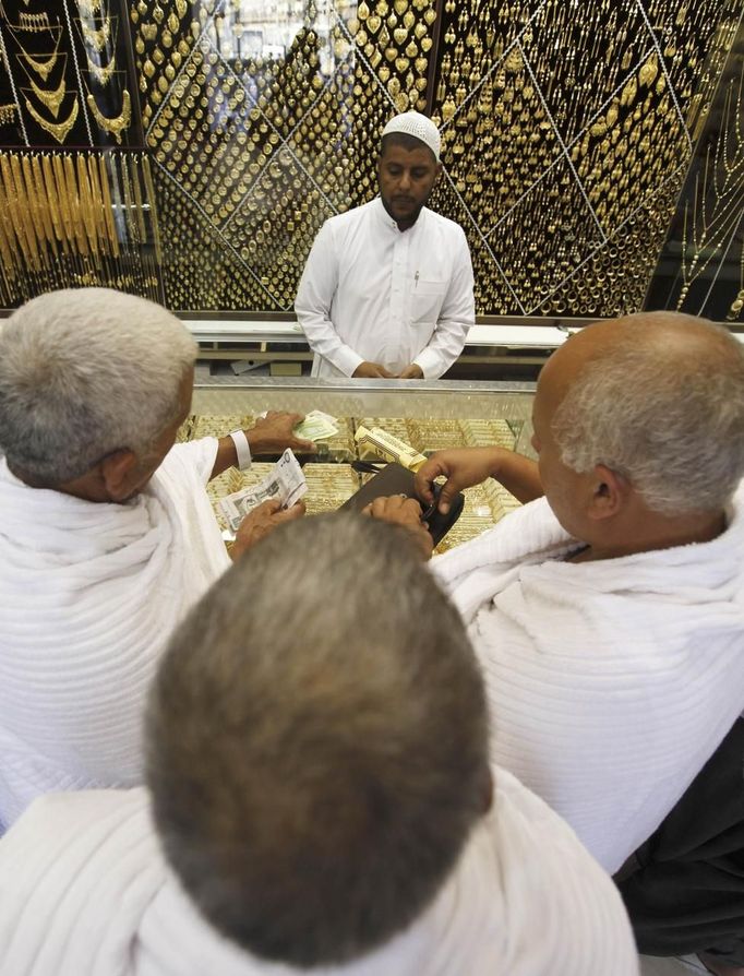 Muslim pilgrims count Saudi Riyal banknotes money as they buy gold from a Saudi jeweller in a jewellery shop at the surrounding area of the Grand Mosque during the annual haj pilgrimage in the holy city of Mecca October 20, 2012. They might wear the humble white sheets required for Islam's haj pilgrimage, but for many visitors thronging Mecca's streets, the perfect souvenir of their trip is that most glittering of commodities: gold. For most pilgrims haj represents the fulfilment of a lifelong ambition and many of them want to commemorate their journey with keepsakes or gifts for relatives that carry a special religious significance. Picture taken October 20, 2012. REUTERS/Amr Abdallah Dalsh (SAUDI ARABIA - Tags: RELIGION BUSINESS) Published: Říj. 23, 2012, 10:57 odp.