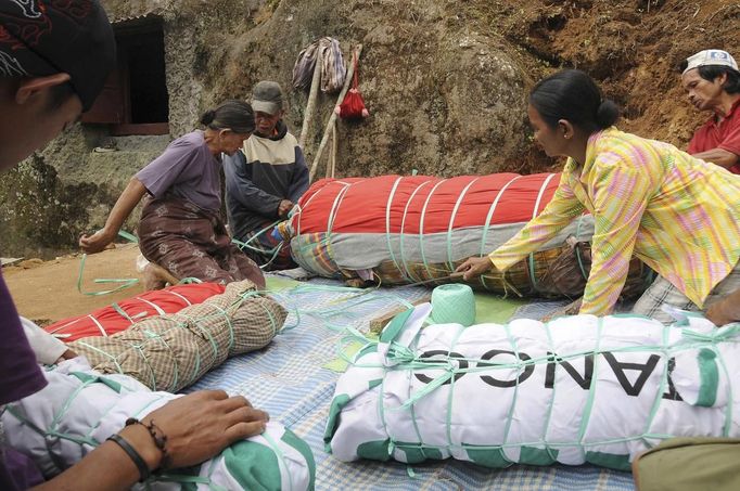 Family members bind cloth rolls containing bodies in front of a stone grave called "Liang" during a ritual in the Toraja district of Indonesia's South Sulawesi Province, August 23, 2012. The ritual, called Ma'nene, involves changing the clothes every three years of mummified ancestors to honor love for the deceased. Locals believe dead family members are still with them, even if they died hundreds of years ago, a family spokesman said. Picture taken August 23, 2012. REUTERS/Yusuf Ahmad (INDONESIA - Tags: SOCIETY RELIGION) Published: Srp. 24, 2012, 1:44 odp.