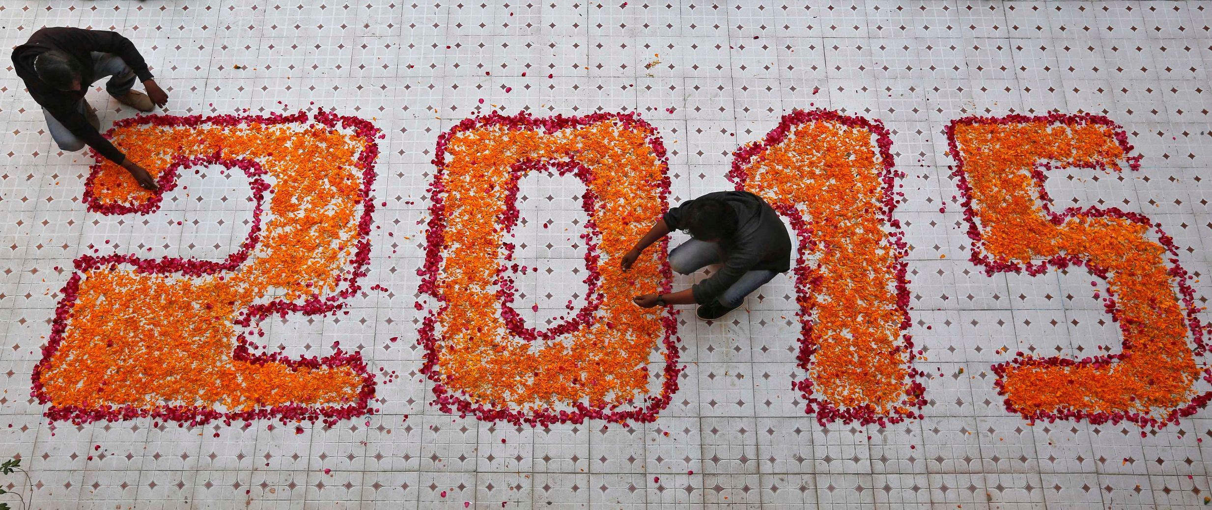 School teachers arrange flower petals in a formation during their New Year's Day celebrations at a school in Ahmedabad
