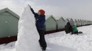 Joe Ottwell, age five, helps build a snowman with his family by beach huts in Brighton, southern England March 12, 2013. Southern England was hit with heavy snow overnight. REUTERS/Luke MacGregor (BRITAIN - Tags: ENVIRONMENT SOCIETY) Published: Bře. 12, 2013, 1:10 odp.