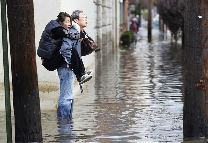 A man carries his wife through the floodwaters in Hoboken, New Jersey, October 31, 2012. The U.S. Northeast began crawling back to normal on Wednesday after monster storm Sandy crippled transportation, knocked out power for millions and killed at least 45 people in nine states with a massive storm surge and rain that caused epic flooding. REUTERS/Gary Hershorn (UNITED STATES - Tags: ENVIRONMENT DISASTER) Published: Říj. 31, 2012, 6:09 odp.