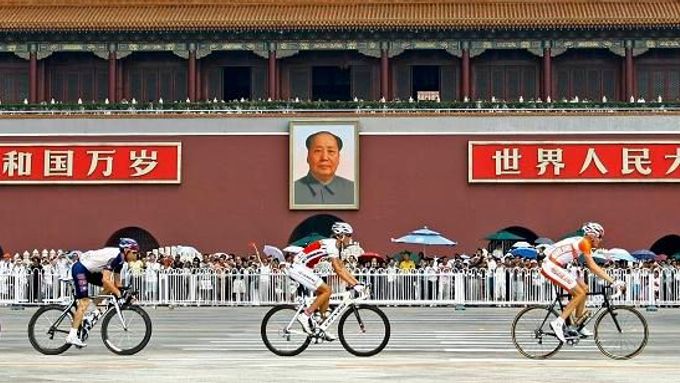 Olympijští cyklisté projíždějí pekingským náměstím Tchien-an-men pod portrétem zakladatele komunistické Číny Mao Ce-tunga.