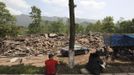 People sit near collapsed buildings after a strong 6.6 magnitude earthquake, at Longmen village, Lushan county, Ya'an, Sichuan province, April 20, 2013. The earthquake hit a remote, mostly rural and mountainous area of southwestern China's Sichuan province on Saturday, killing at least 102 people and injuring about 2,200 close to where a big quake killed almost 70,000 people in 2008. REUTERS/Stringer (CHINA - Tags: DISASTER) CHINA OUT. NO COMMERCIAL OR EDITORIAL SALES IN CHINA Published: Dub. 20, 2013, 9:22 dop.