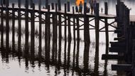 Ženy kráčí přes most z týkových sloupů přes jezero Taungthaman v Amarapuře, 11km jižně od Mandalay, 3. října 2007.