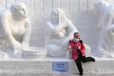 Návštěvník pózuje před ledovou sochou nazvanou Finaská lázeň. Festival v čínském Harbinu startuje 5. ledna.
