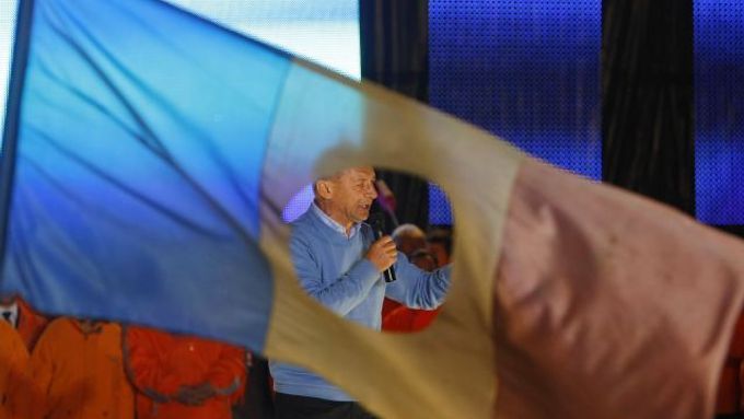 Traian Basescu na předvolebním mítinku. Vlajka s dírou uprostřed byla symbolem revoluce v roce 1989. Povstalci z ní vystříhávali komunistický znak.
