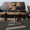 People walk past the Festival Palace displaying a giant canvas of the official poster of the 67th Cannes Film Festival featuring actor Marcello Mastroianni in Cannes