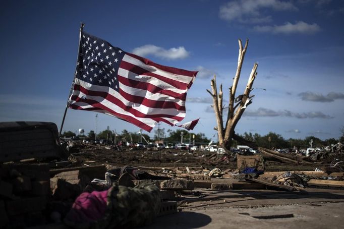 A flag is placed in the foundation of a flattened home day after a tornado devastated the town Moore, Oklahoma, on the outskirts of Oklahoma City May 21, 2013. Rescuers went building to building in search of victims and thousands of survivors were homeless on Tuesday after a massive tornado tore through the Oklahoma City suburb of Moore, wiping out whole blocks of homes and killing at least 24 people. REUTERS/Adrees Latif (UNITED STATES - Tags: DISASTER ENVIRONMENT TPX IMAGES OF THE DAY) Published: Kvě. 22, 2013, 5:09 dop.