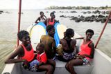 Mladé ženy sedí na lodi a připravují se na trénink surfařské školy Black Girls Surf. Učit je bude právě první senegalská profesionální surfařka.
