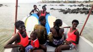 Mladé ženy sedí na lodi a připravují se na trénink surfařské školy Black Girls Surf. Učit je bude právě první senegalská profesionální surfařka.