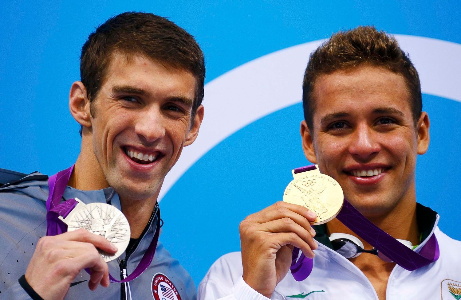 Americký plavec Michael Phelps pózuje se stříbrnou medailí a vedle něj Jihoafričan Chad le Clos se zlatou za 200 metrů motýlek na OH 2012 v Londýně.