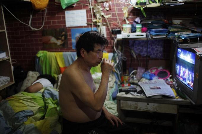 Xiao Cao, a 57-year-old gay man, shaves as he sits next to his partner in his eight-square-metre apartment in Shanghai April 22, 2012. China's gay community has long been on the edges of society but it is gradually becoming more accepted. Cao, who is an unemployed drag queen, is one whose life lifts the curtain on a less romanticised view of Chinese homosexuals. Living in an eight-square-metre apartment behind a public toilet and with a monthly income of 500 yuan ($79) from social insurance, he passes his days dancing in public and spending time with friends at gay clubs. Picture taken April 22, 2012. REUTERS/Aly Song (CHINA - Tags: SOCIETY) CHINA OUT. NO COMMERCIAL OR EDITORIAL SALES IN CHINA. ATTENTION EDITORS PICTURE 25 OF 28 OF PACKAGE 'GAY AND OUT IN CHINA' TO FIND ALL IMAGES SEARCH 'GAY OUT CHINA' Published: Čer. 1, 2012, 12:42 dop.