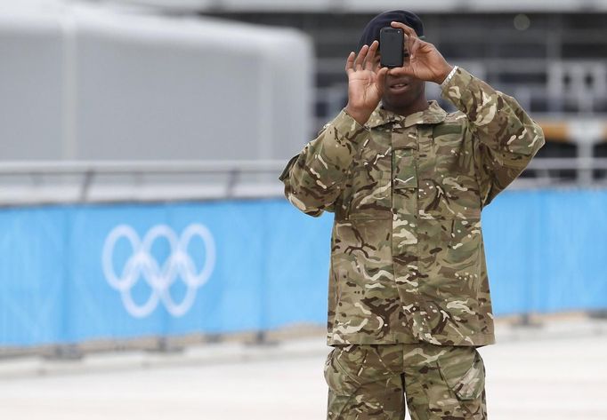 A members of the armed forces takes a photograph at the Olympic Park in Stratford, the location of the London 2012 Olympic Games, in east London July 15, 2012. The head of private security firm G4S said on Saturday his firm only realised just over a week ago it would not be able to supply enough venue guards for this month's London Olympics, as he publicly apologised for the embarrassing failure. On Thursday, the government said it would deploy additional troops after it became clear G4S was unlikely to provide the expected 10,400 guards it was contracted to do because of problems processing applicants. REUTERS/Andrew Winning (BRITAIN - Tags: MILITARY POLITICS SOCIETY SPORT OLYMPICS) Published: Čec. 15, 2012, 2:21 odp.