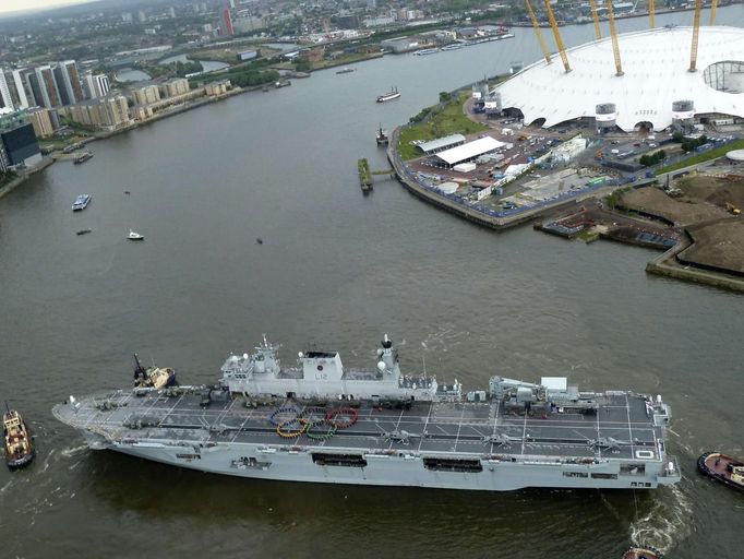 Crew form the Olympic rings on the flight deck of the Royal Navy helicopter assault ship HMS Ocean as it arrives to its berth on the river Thames in London July 13, 2012. Security surrounding the Olympics has made the headlines this week after Britain was forced to deploy 3,500 extra troops to fill an embarrassing last-minute shortfall in private security staff. Picture taken July 13, 2012. REUTERS/MoD/Crown Copyright/handout (BRITAIN - Tags: MILITARY SPORT OLYMPICS POLITICS) NO ARCHIVES. FOR EDITORIAL USE ONLY. NOT FOR SALE FOR MARKETING OR ADVERTISING CAMPAIGNS. THIS IMAGE HAS BEEN SUPPLIED BY A THIRD PARTY. IT IS DISTRIBUTED, EXACTLY AS RECEIVED BY REUTERS, AS A SERVICE TO CLIENTS Published: Čec. 14, 2012, 10:07 dop.