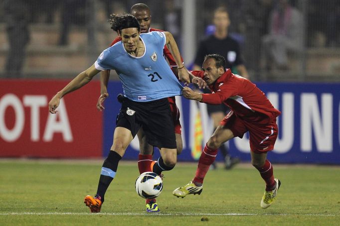 Edinson Cavani z Uruguaye boju je o míč s Adnanem Adousem v baráži o MS