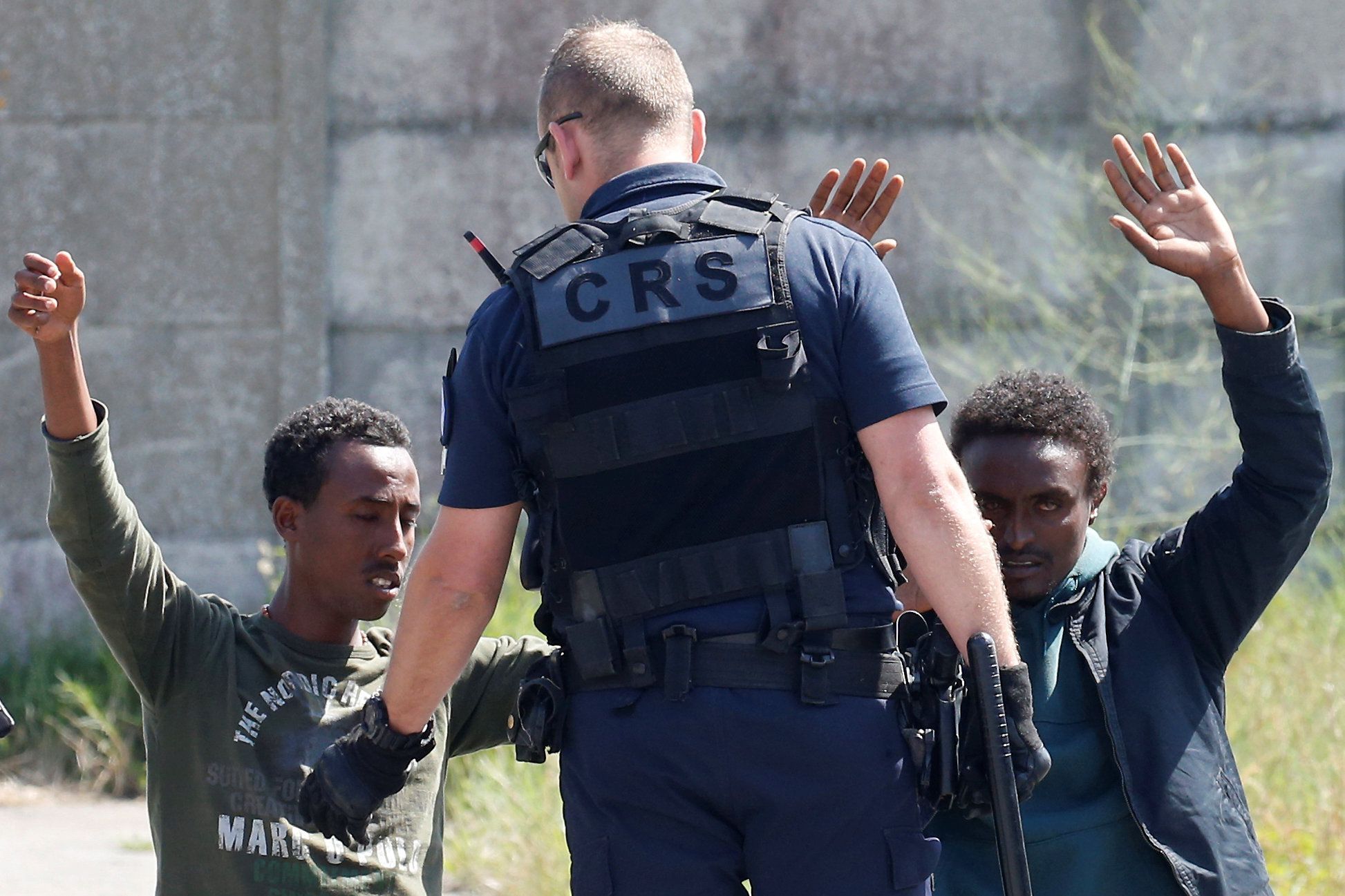 Francouzský policista a dva migranti v Calais.