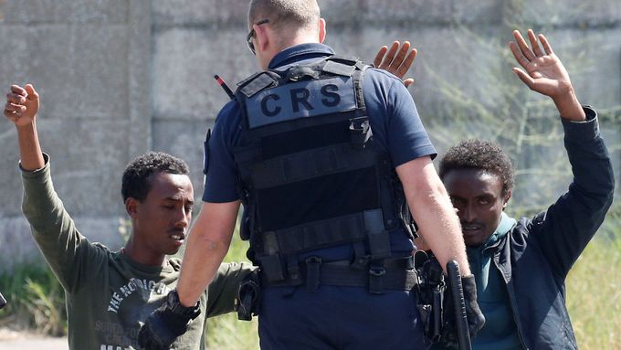 Francouzský policista a dva migranti v Calais.