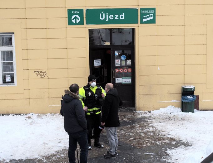 Policista hlídkující před vstupem do haly lanové dráhy.