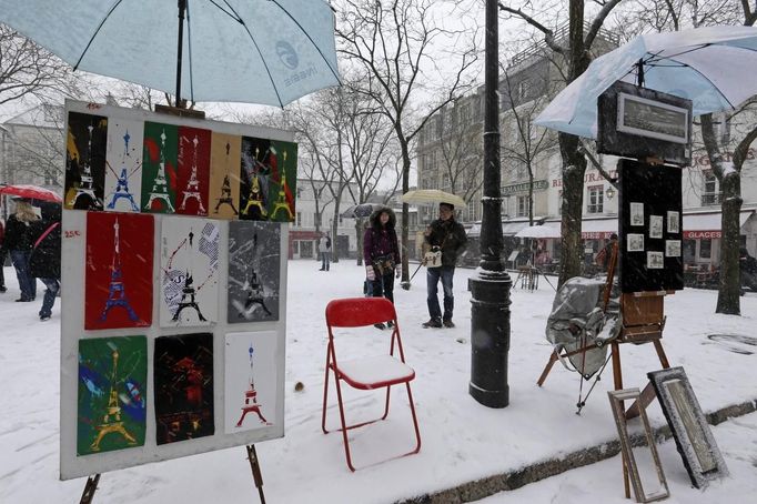 Paintings are displayed on the snow-covered 'Place du Tertre', a square at the Butte Montmartre area near the Sacre Coeur basilica in Paris March 12, 2013 as winter weather with snow and freezing temperatures returns to northern France. REUTERS/Jacky Naegelen (FRANCE - Tags: ENVIRONMENT) Published: Bře. 12, 2013, 11:38 dop.