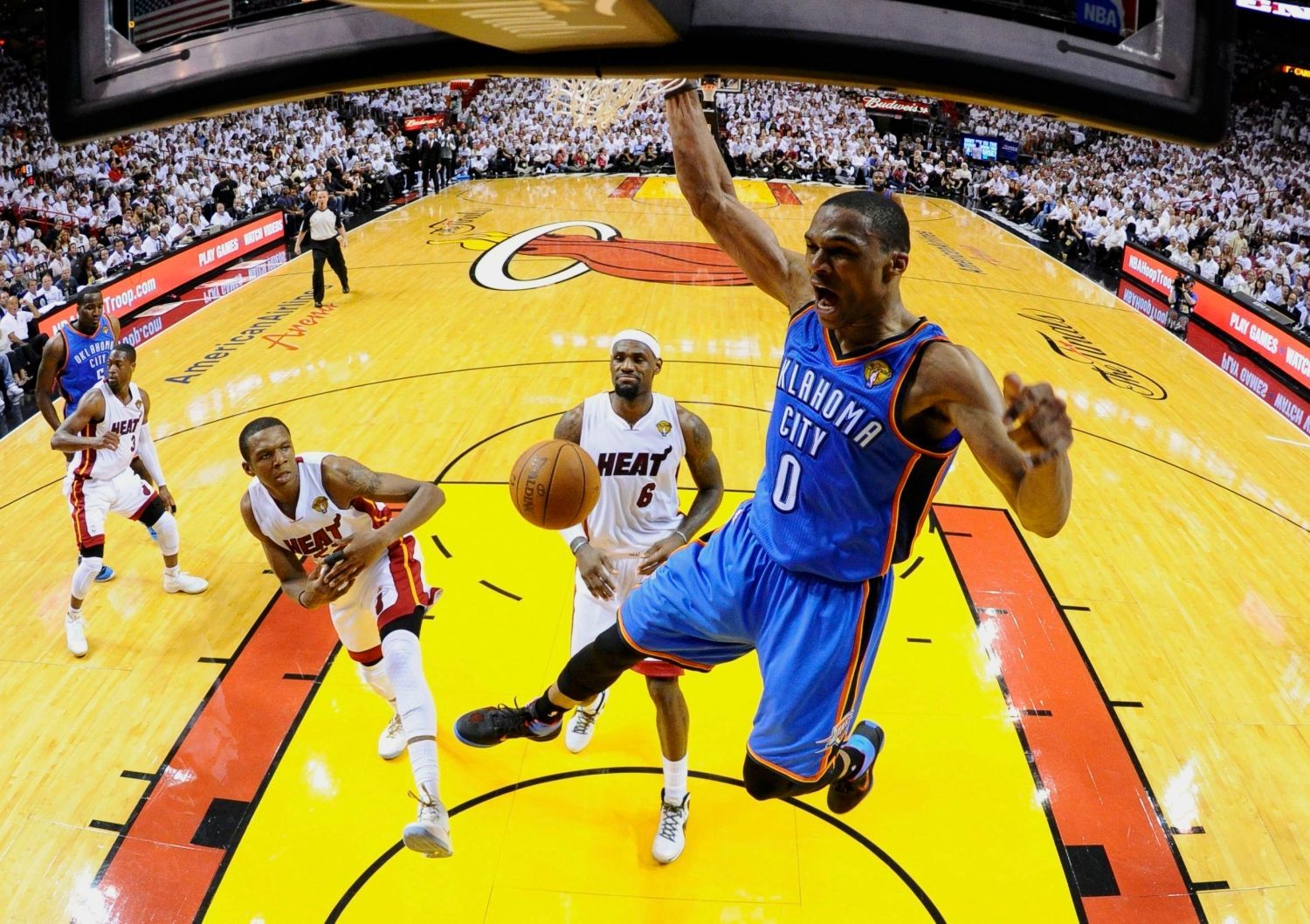 Basketbalista Russell Westbrook z Oklahomy slaví koš proti Miami ve fnále play-off NBA. V pozadí James Jones (vlevo) a LeBron James.