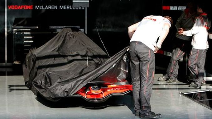 Mechanici halí v boxech ve Spa monopost McLaren pod plachtu. Tým kvůli špionážní kauze přišel o všechny letošní body v Poháru konstruktérů.