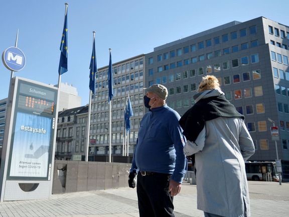 Lidé v rouškách před sídlem Evropské komise v Bruselu.