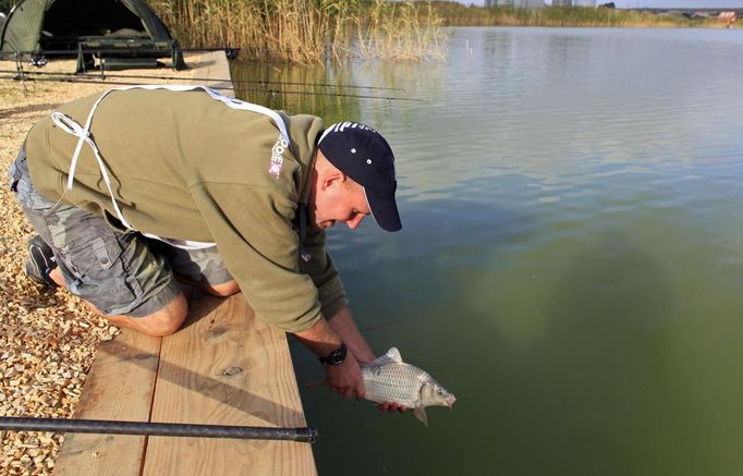 Kevin Hewitt of England releases an underweight carp during the 14th Carpfishing World Championship in Corbu village, 310 km (192 miles) east of Bucharest, September 29, 2012. REUTERS/Radu Sigheti (ROMANIA - Tags: SOCIETY) Published: Zář. 29, 2012, 4:36 odp.