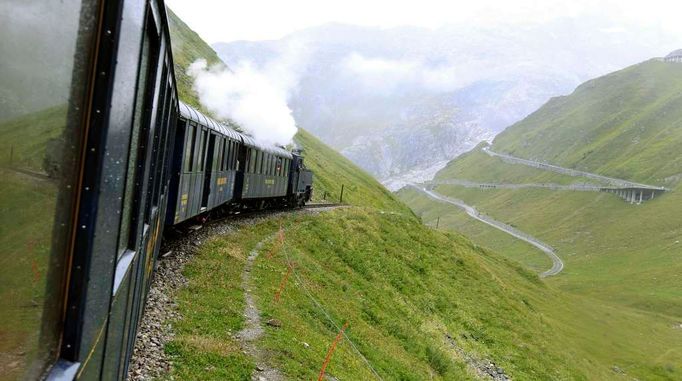 Parní vlak na železnici Dampfbahn Furka Bergstrecke (DFB) sjíždí dolů po trati z vysokohorského průsmyku Furkapass. Po šedesátileté pauze parní vlaky znovu opět vyrazily přes Furkapass ve švýcarských.