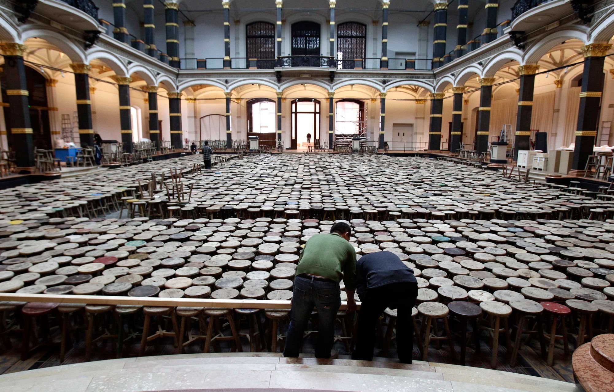 Assistants work on installation made of wooden stools by Chinese artist Ai Weiwei as part of exhibition 'Evidence'  at Martin-Gropius Bau in Berlin