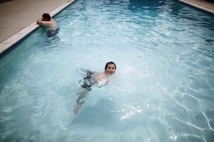 Davidson Aero Smith (R), 7, swims in the pool at Village Trailer Park in Santa Monica, California, July 13, 2012. Developer Marc Luzzatto wants to relocate residents from the trailer park to make way for nearly 500 residences, office space, stores, cafes and yoga studios, close to where a light rail line is being built to connect downtown Los Angeles to the ocean. Village Trailer Park was built in 1951, and 90 percent of its residents are elderly, disabled or both, according to the Legal Aid Society. Many have lived there for decades in old trailers which they bought. The property is valued at as much as $30 million, according the LA Times. REUTERS/Lucy Nicholson (UNITED STATES - Tags: SOCIETY REAL ESTATE BUSINESS POLITICS) Published: Čec. 14, 2012, 7:52 dop.