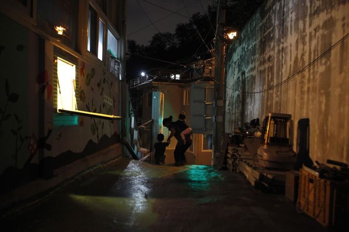 A "baby box" (L) is seen at Joosarang church as preacher Jeong Young-ran and two children, who were abandoned at the church years earlier and have been raised there ever since, go out for a walk in Seoul September 20, 2012. Pastor Lee Jong-rak, who runs the "baby box" at the church where mothers can leave unwanted infants, has seen a sharp increase in the number of newborns being left there because, the pastor says, of a new law aimed protecting the rights of children. South Korea is trying to shed a reputation of being a source of babies for adoption by people abroad. It is encouraging domestic adoption and tightening up the process of a child's transfer from birth mother to adoptive parents. Picture taken September 20, 2012. REUTERS/Kim Hong-Ji (SOUTH KOREA - Tags: SOCIETY) Published: Říj. 7, 2012, 6:58 dop.