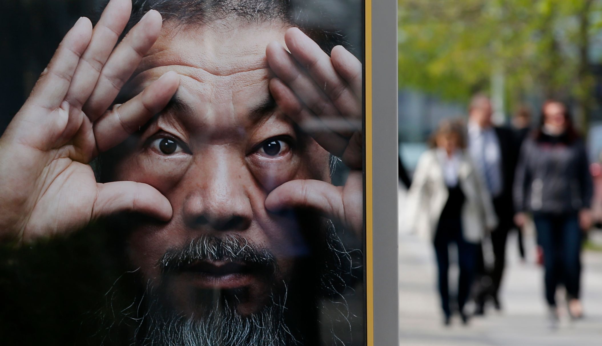 People walk beside an advertising poster for the exhibition 'Evidence' by Chinese artist Ai Weiwei at the Martin-Gropius Bau in Berlin
