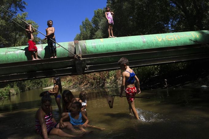 Children play at the river that borders the Spanish gypsy settlement of Puerta de Hierro outside Madrid August 12, 2012. Fifty-four families have been living in Puerta de Hierro, on the banks of the Manzanares river for over 50 years. Since the summer of 2010, the community has been subject to evictions on the grounds that the dwellings are illegal. Families whose houses have been demolished, move in with relatives whose houses still remain while the debris keeps piling up around them as more demolitions take place. Picture taken August 12, 2012. REUTERS/Susana Vera (SPAIN - Tags: SOCIETY) ATTENTION EDITORS - PICTURE 20 OF 31 FOR PACKAGE 'GYPSY SITE DEMOLISHED' SEARCH 'GYPSY SITE' FOR ALL IMAGES Published: Lis. 5, 2012, 4:12 odp.