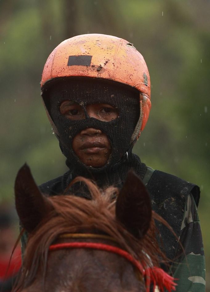 A child jockey sits on his horse after a race at Panda racetrack outside Bima, November 18, 2012. Dozens of child jockeys, some as young as eight-years-old take part in the races. Involving nearly 600 horses they take place around a dusty, oval track of 1,400 meters (nearly one mile). The reward, for the winner is a handful of cash for his family, and glory for the jockey. The grand prize is one million rupiah ($100). Those who win their groups get two cows. The chairman of the races' organising team, Hajji Sukri, denies that there is any danger to the children saying they are all skilful riders and none has been killed or seriously hurt. Picture taken November 18, 2012. REUTERS/Beawiharta (INDONESIA - Tags: SPORT SOCIETY) ATTENTION EDITORS: PICTURE 18 of 25 FOR PACKAGE 'BETTING ON CHILD JOCKEYS' Published: Lis. 24, 2012, 9:16 dop.