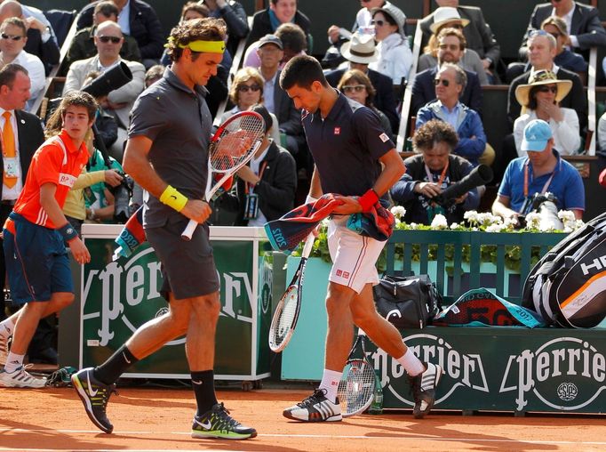 Roger Federer a Novak Djokovič se míjejí během semifinále French Open 2012.