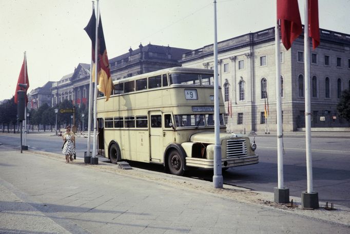 Fotografie zobrazuje dvoupatrový autobus na ulici Unter den Linden ve východním Berlíně poblíž Bebelplatz. Vlevo je městská knihovna, vpravo Humboldtova univerzita. 1961